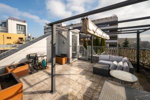 patio con sofá y balcón con parrilla en Sky Garden Premium Penthouse, en Varsovia