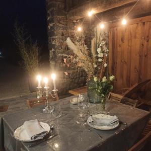 una mesa con platos y vasos y velas en Suite privative sur Domaine Au chant de l'eau avec possibilité séjour bien-être, en Siaugues Ste Marie