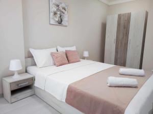 een witte slaapkamer met een groot wit bed met roze kussens bij DiP HOME APARTMENTS in Pomorie