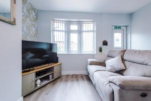 a living room with a couch and a flat screen tv at 4 bed property, Bolton , Manchester in Egerton