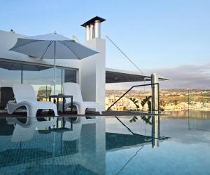 a swimming pool with two chairs and an umbrella at Mykonos Suite in Paphos