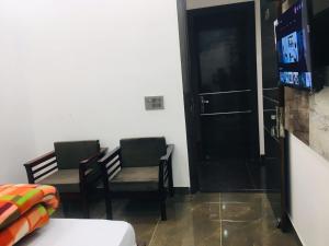 Zimmer mit 2 Stühlen und einer Tür mit einem TV in der Unterkunft RV Lodge in Bulandshahr