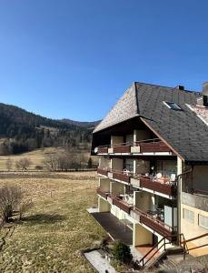 ein Gebäude mit einem Balkon mit Blick auf ein Feld in der Unterkunft Ferienwohnung Schwinbachblick Menzenschwand in St. Blasien