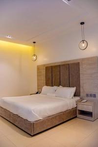 ein großes Bett in einem Schlafzimmer mit zwei Leuchten in der Unterkunft Polo Grand Hotel in Maiduguri