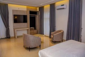 sypialnia z łóżkiem, 2 krzesłami i telewizorem w obiekcie Polo Grand Hotel w mieście Maiduguri