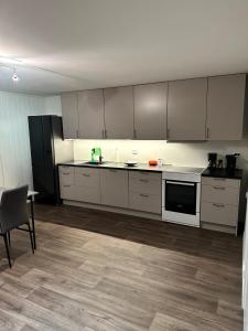a kitchen with white cabinets and a table and a chair at Your home away from home, apartment 2 in Tromsø