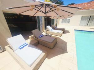 two lounge chairs and an umbrella next to a swimming pool at Villa Reis - The Villa of Kings in Bedfordview