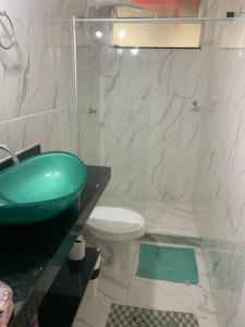 a bathroom with a green sink and a toilet at Apartamento Jardim Camburi 2 quartos in Vitória +2 photos