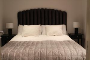 a bed with a large black headboard with white pillows at Studio Hamra in Särö