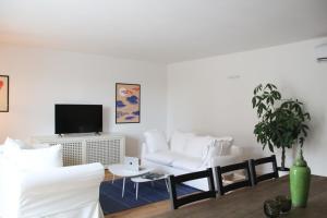 a living room with a white couch and a tv at Waterfront balcony I Grani 2 Resort Style Suite in Livorno