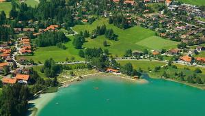 una vista aerea su un villaggio e un lago di Ferienhäuser im Feriendorf Weissensee im Allgäu F2 a Hafenegg