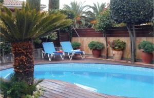 einen Pool mit zwei Stühlen und einer Palme in der Unterkunft Amazing Home In Tossa De Mar in Tossa de Mar