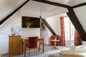 Un dormitorio con una cama, un escritorio y un televisor. en The Red Lion Hotel, en Spalding