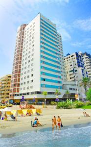 eine Gruppe von Menschen am Strand mit einem großen Gebäude in der Unterkunft Hotel Cartagena Plaza in Cartagena de Indias