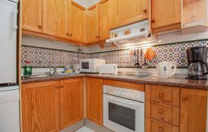 eine Küche mit Holzschränken und weißen Geräten in der Unterkunft 2 Bedroom Nice Home In La Florida in La Florida