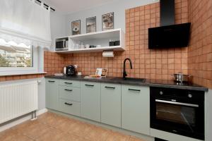 een keuken met witte kasten en een tv aan de muur bij Apartment in Gdańsk with 3 Bedrooms, Furnished Balcony and 2 Desks by Rent like home in Gdańsk