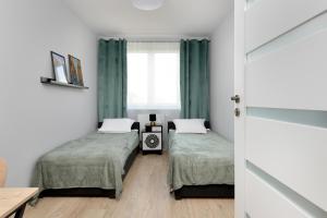 een kamer met 2 bedden en een raam bij Apartment in Gdańsk with 3 Bedrooms, Furnished Balcony and 2 Desks by Rent like home in Gdańsk