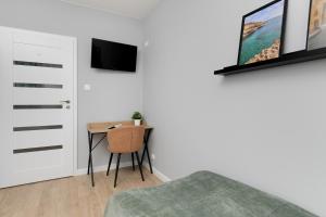 een slaapkamer met een bed en een tafel en een televisie bij Apartment in Gdańsk with 3 Bedrooms, Furnished Balcony and 2 Desks by Rent like home in Gdańsk