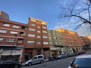 a group of buildings on a city street with cars parked at Apartamento Cleo Gijón in Gijón