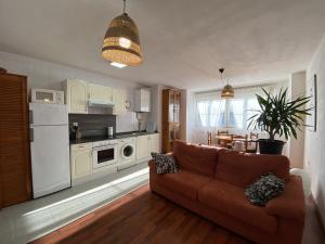 a living room with a couch and a kitchen at Apartamento Cleo Gijón in Gijón