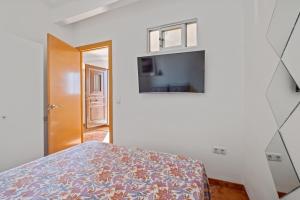 a bedroom with a bed and a flat screen tv at Apartamento frente a la playa in Málaga