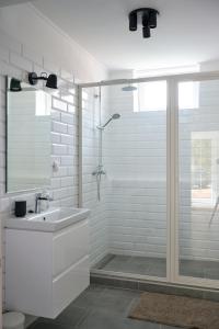 een witte badkamer met een douche en een wastafel bij Kúria apartmanház in Bük