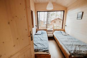 two beds in a small room with a window at WYPOCZYWANKO w BORSKU domek 24 in Borsk