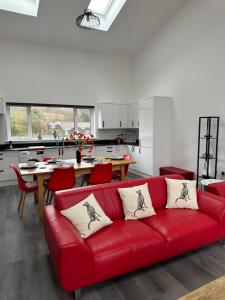 a red couch in a living room with a kitchen at Poppy Lodge faversham in Boughton Street