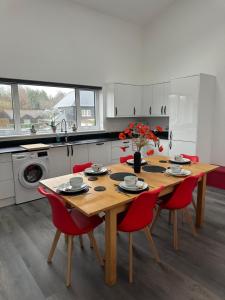 a kitchen with a wooden table and red chairs at Poppy Lodge faversham in Boughton Street