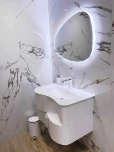 een witte badkamer met een wastafel en een spiegel bij DiP HOME APARTMENTS in Pomorie