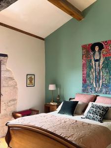 a bedroom with a bed with a painting on the wall at Les Hauts de Broze in Broze