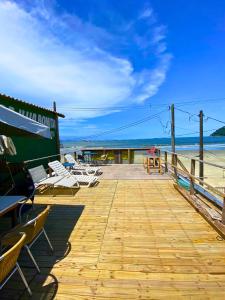een houten terras met stoelen en tafels op het strand bij Restaurante e Pousada - Ilha Bonita in Guarujá