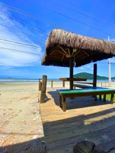 uma mesa de piquenique com um guarda-sol de palha na praia em Restaurante e Pousada - Ilha Bonita no Guarujá