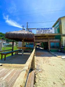um restaurante com um banco e um telhado de palha em Restaurante e Pousada - Ilha Bonita no Guarujá