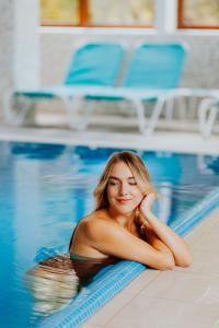 une femme qui se couche dans une piscine dans l'établissement Hotel O3zone, à Băile Tuşnad