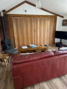 a living room with a red couch and a wooden table at Stable lodge 2 Bedrooms in Horspath