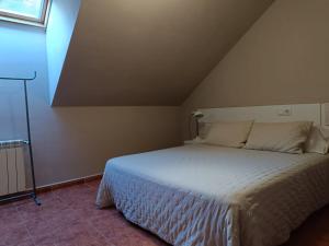 una camera da letto con letto bianco in mansarda di Apartamentos Astilleros a Candás