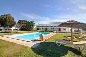 a swimming pool with an umbrella and chairs and a house at Casa Laranja Canela in Alvor