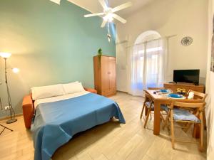 a bedroom with a bed and a table and a ceiling fan at Le Case di Anan, Castellammare del Golfo in Castellammare del Golfo