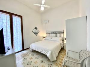 a bedroom with a bed and a chair and a window at Le Case di Anan, Castellammare del Golfo in Castellammare del Golfo