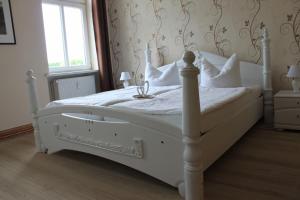 a white bed in a bedroom with a window at Ferienwohnung im Gutshaus Mühlhof in Prenzlau