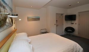 a bedroom with a white bed and a flat screen tv at Tudor Lodge Bed & Breakfast in Manorbier
