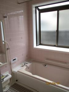 baño con bañera, ventana y azulejos rosados en Private inn “Come! Akae House” - Vacation STAY 61227v, en Toyama