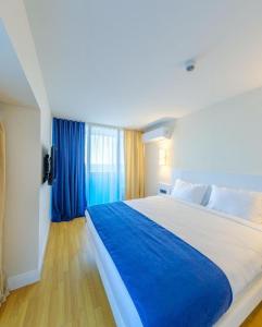 um quarto com uma cama grande e cortinas azuis em Luxury PANORAMA sea view apartment & Central Batumi em Batumi