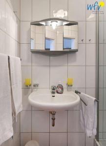 Baño blanco con lavabo y espejo en Ferienpark Seedorf Haus Granitz - Ferienwohnung 2, en Sellin