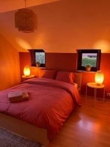 ein Schlafzimmer mit einem großen roten Bett und zwei Lampen in der Unterkunft La Cardamine in Marche-en-Famenne