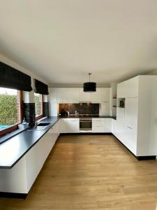 duża kuchnia z białymi szafkami i drewnianą podłogą w obiekcie La Cardamine w mieście Marche-en-Famenne
