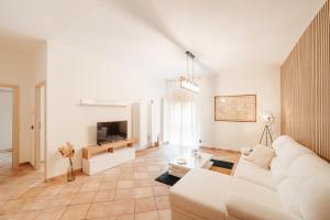 a white living room with a white couch and a tv at CR32 TOURIST ACCOMODATION in Civitavecchia