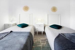 2 Betten in einem weißen Zimmer mit grünen Kissen in der Unterkunft A O - Augusta in Peniche