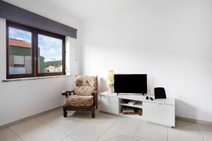 ein Wohnzimmer mit Sessel und Fernseher in der Unterkunft A O - Augusta in Peniche
